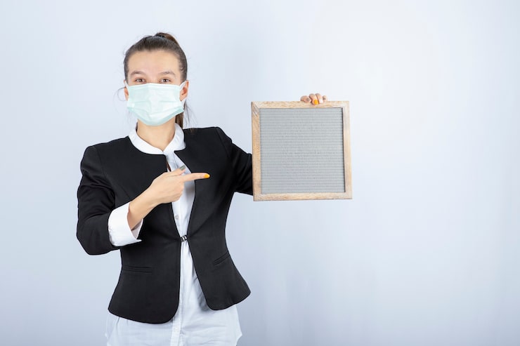 Photo Gratis potret wanita muda memakai masker wajah memegang bingkai di atas dinding putih. foto berkualitas tinggi