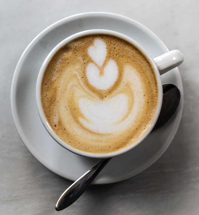 Foto gratuito precioso sabroso café cappuccino en blanco taza con cuchara en la pestaña
