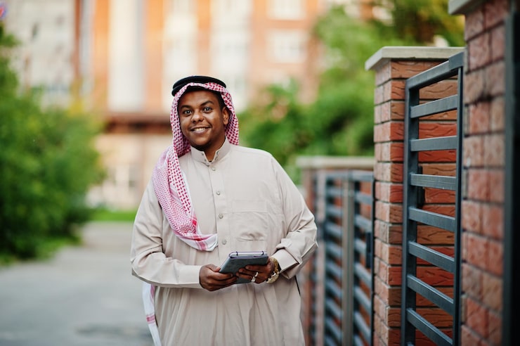 Photo Gratis pria arab timur tengah berpose di jalanan dengan latar belakang bangunan modern sambil memegang tablet