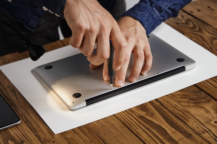Photo Gratis pria menutup penutup atas laptop ramping metalik untuk merakitnya kembali setelah memperbaiki, membersihkan, dan memperbaiki servis di labnya