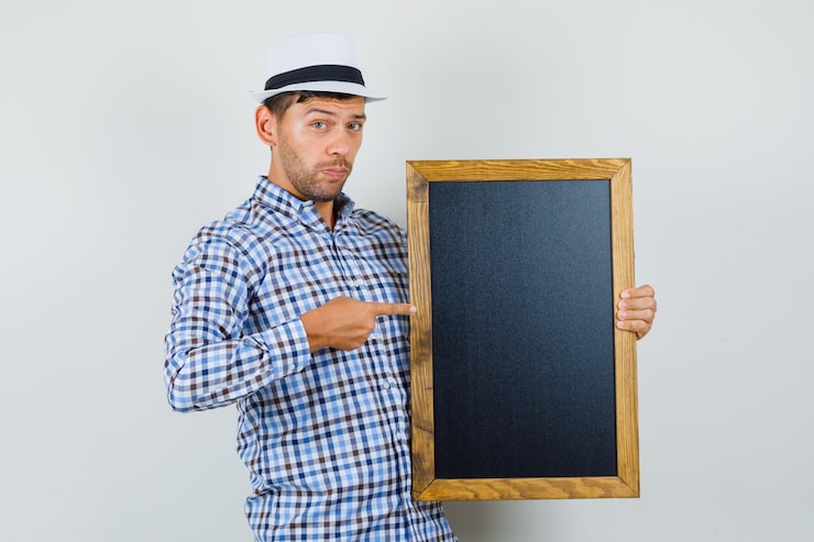 Photo Gratis pria muda menunjuk ke papan tulis dengan kemeja kotak-kotak