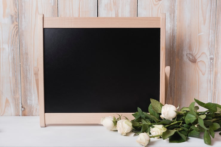 Foto gratuito ramo de rosas con pizarra pequeña de madera en escritorio blanco