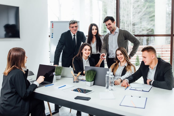 Foto gratuito reunión de personal. grupo de jóvenes modernos en ropa casual elegante discutiendo algo mientras trabaja en la oficina creativa. tiempo de negocios.