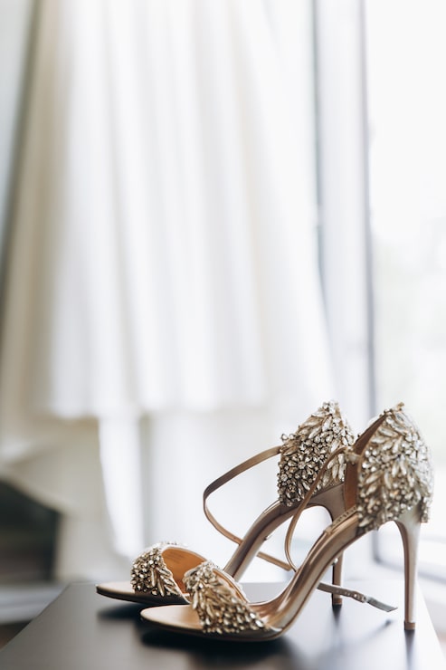 Foto gratuito riques zapatos brillantes con cristales de pie ante un vestido colgado