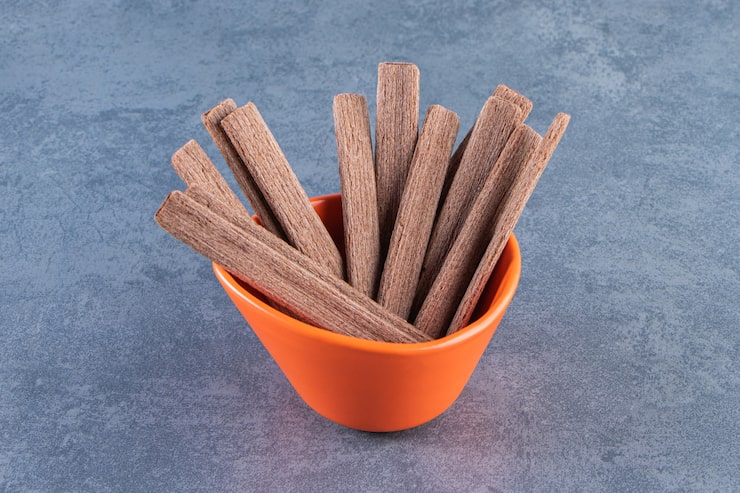 Foto gratuito rollo de obleas de chocolate dulce en un recipiente, sobre el fondo de mármol.