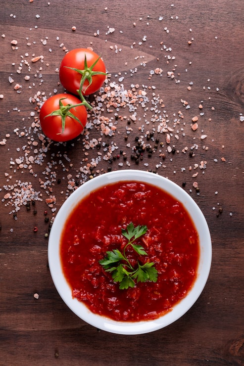 Foto gratuito salsa de tomate y tomates cherry en polvo de pimienta negra sobre superficie de piedra marrón