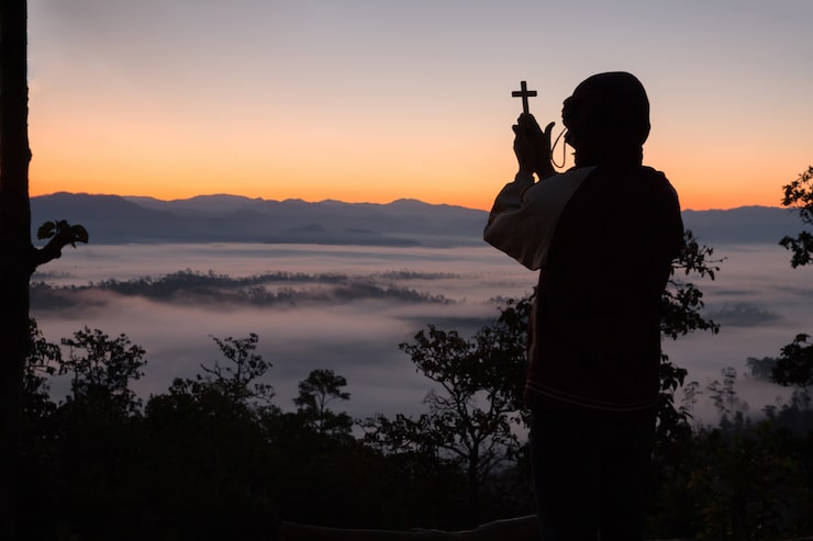 Foto gratuito silueta de mano humana sosteniendo la cruz, el fondo es el amanecer