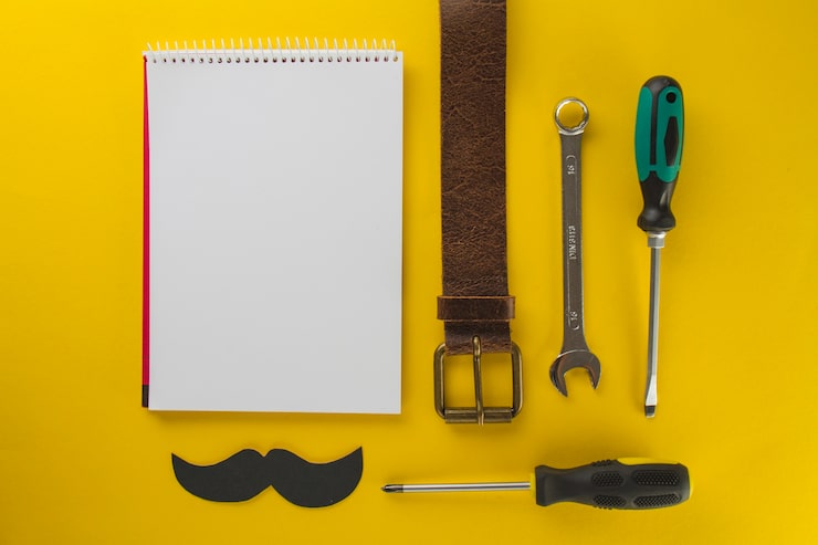 Foto gratuito superficie amarilla con cuaderno en blanco y herramientas para el día del padre