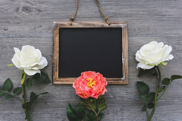 Foto gratuito superficie de madera con pizarra en blanco y tres flores