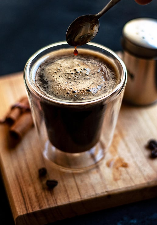 Foto gratuito taza de café espresso doble con palitos de canela y granos de café en una tabla de madera