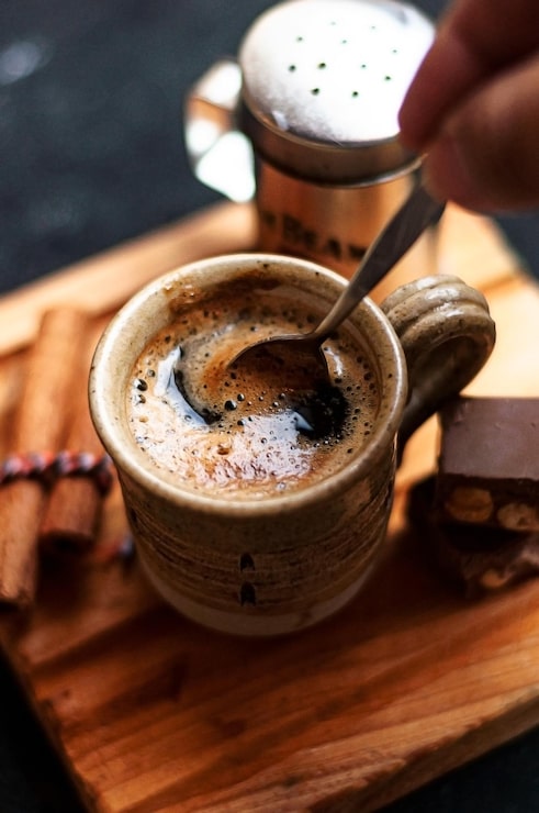 Foto gratuito taza de café con palitos de canela y galletas de chocolate en una tabla de madera