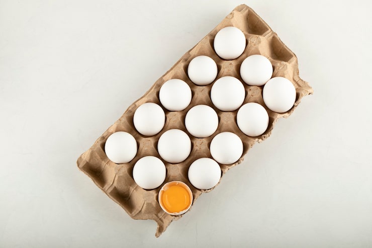 Photo Gratis telur ayam mentah dalam kotak telur di atas permukaan putih.