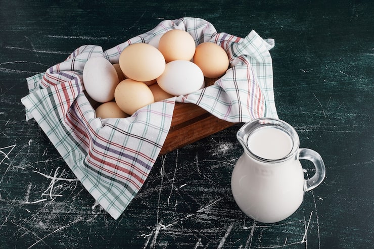 Photo Gratis telur dalam nampan kayu dengan toples susu di sekelilingnya.