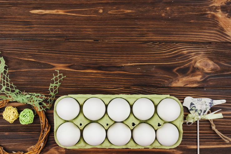 Photo Gratis telur putih dalam rak di atas meja kayu