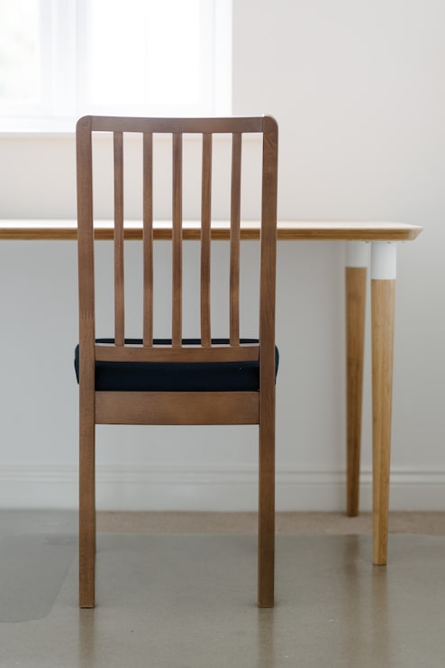 Foto gratuito tiro vertical de una silla de madera y una mesa en una habitación blanca y tranquila
