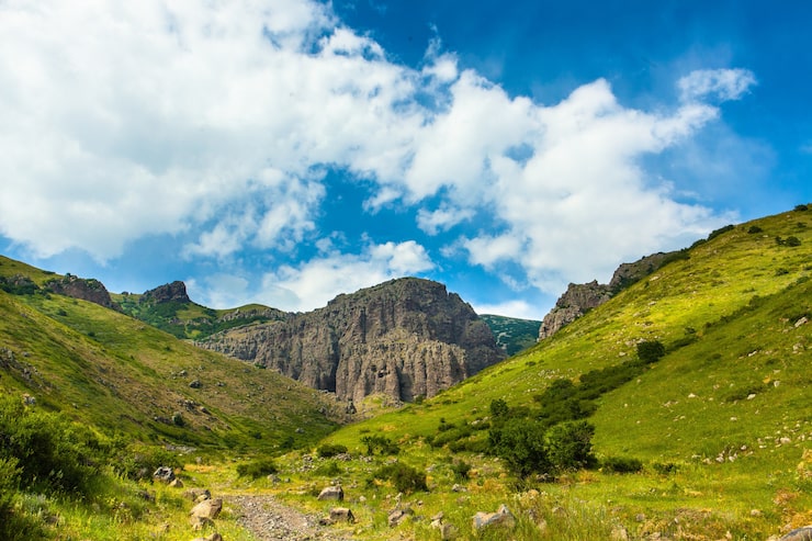 Foto gratuito tomada horizontal de montañas cubiertas de verde bajo el hermoso cielo nublado