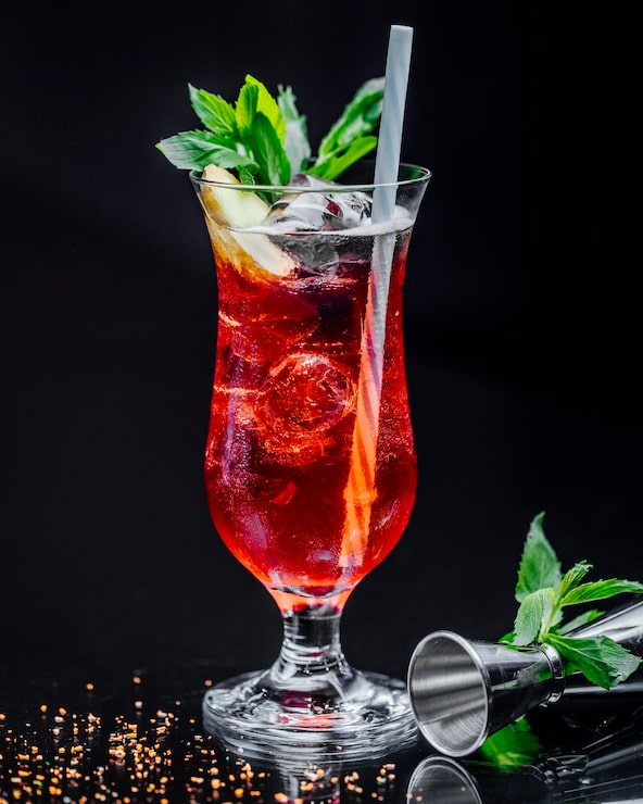 Foto gratuito un vaso de bebida roja con hojas de menta y pipa.