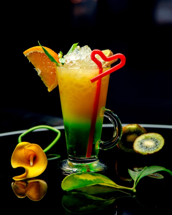 Foto gratuito un vaso de cóctel de kiwi y naranja adornado con rodaja de naranja y kiwi