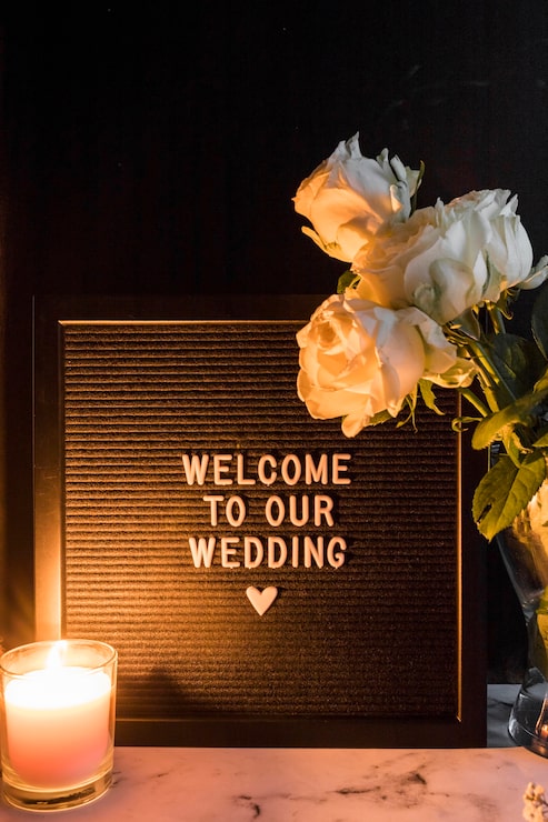Foto gratuito vela encendida y rosas cerca del marco negro con la bienvenida a nuestro mensaje de boda