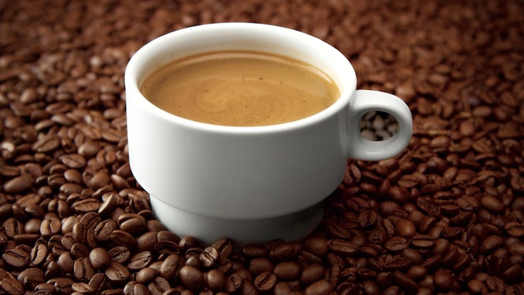 Foto gratuito vista lateral de la taza blanca de café negro sobre granos de café crema de café moviéndose en la taza