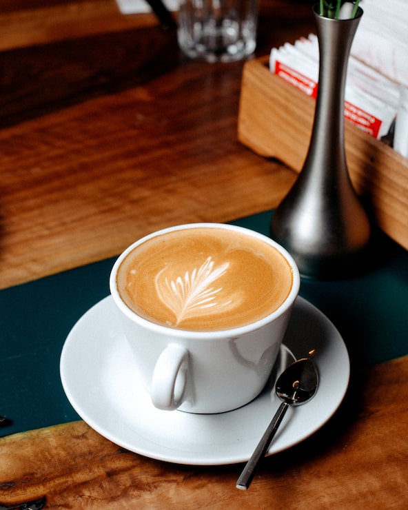 Foto gratuito vista lateral de una taza de café con leche en una mesa de madera