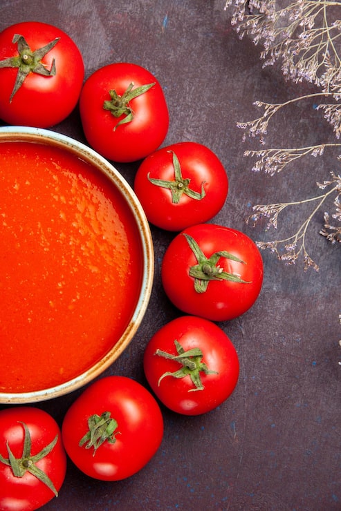 Foto gratuito vista superior deliciosa sopa de tomate en un círculo con tomates rojos frescos en el fondo oscuro salsa de plato de comida de sopa de tomates