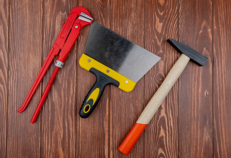 Foto gratuito vista superior de las herramientas de construcción como llave, cuchillo de putty y martillo de ladrillo en fondo de madera