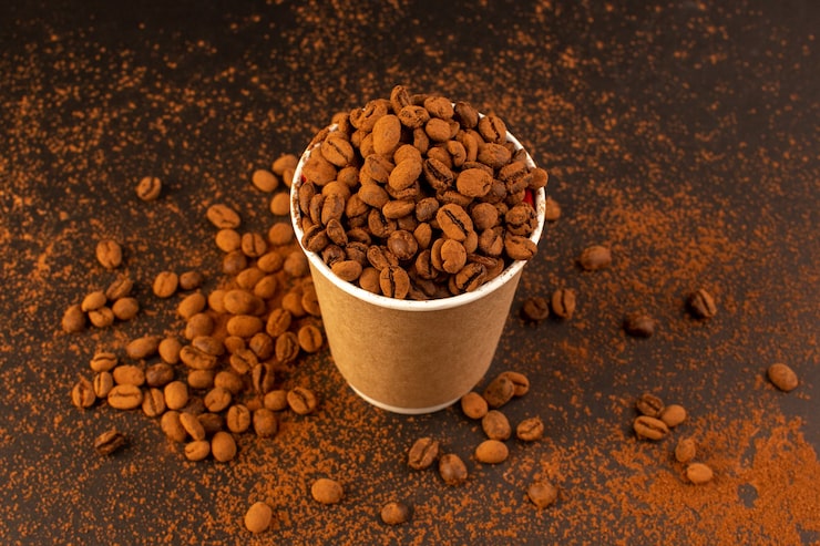 Foto gratuito una vista superior de semillas de café marrón dentro de un vaso de plástico sobre la mesa marrón