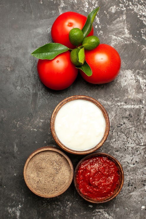 Foto gratuito vista superior de tomates rojos frescos con condimentos en vegetales rojos maduros de superficie oscura