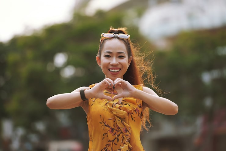 Photo Gratis wanita asia muda bergaya tersenyum menunjukkan isyarat hati