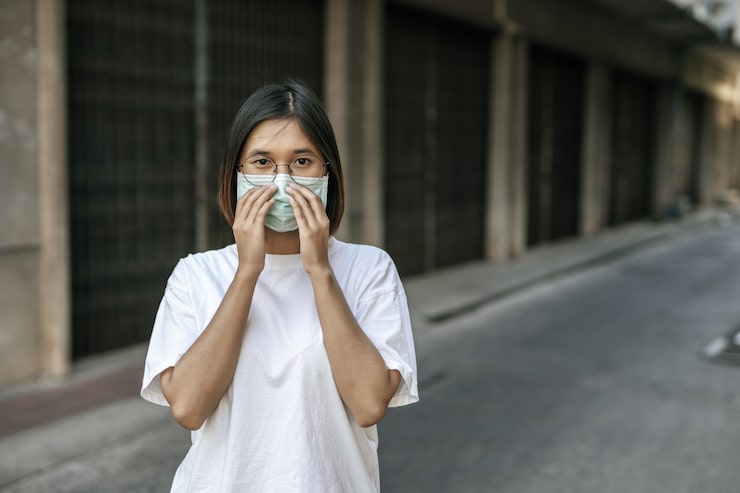 Photo Gratis wanita mengenakan masker di jalan.