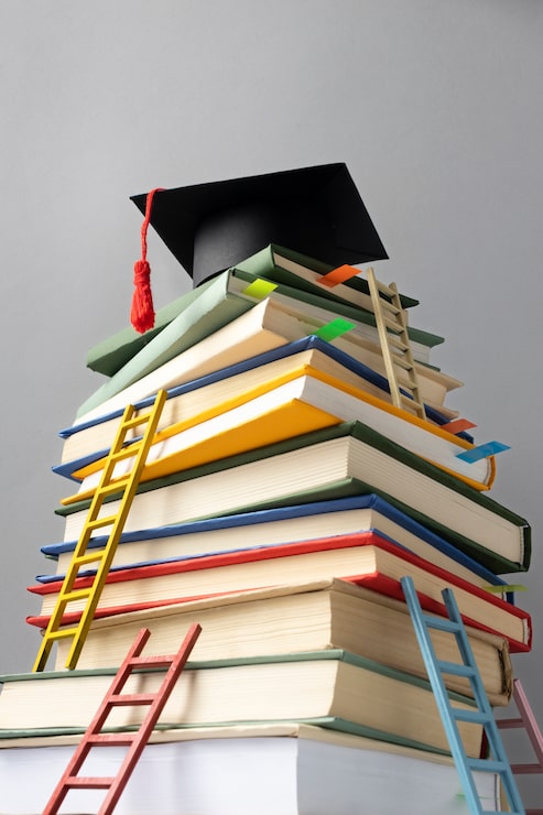 Foto gratuito angolo basso di libri impilati, un cappello di laurea e scale per la giornata dell'istruzione
