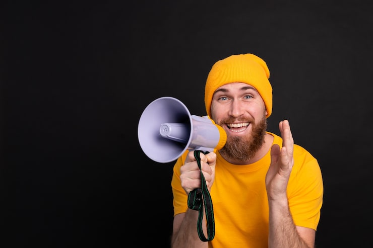 Foto gratuito attenzione! uomo europeo che grida nel megafono su priorità bassa nera
