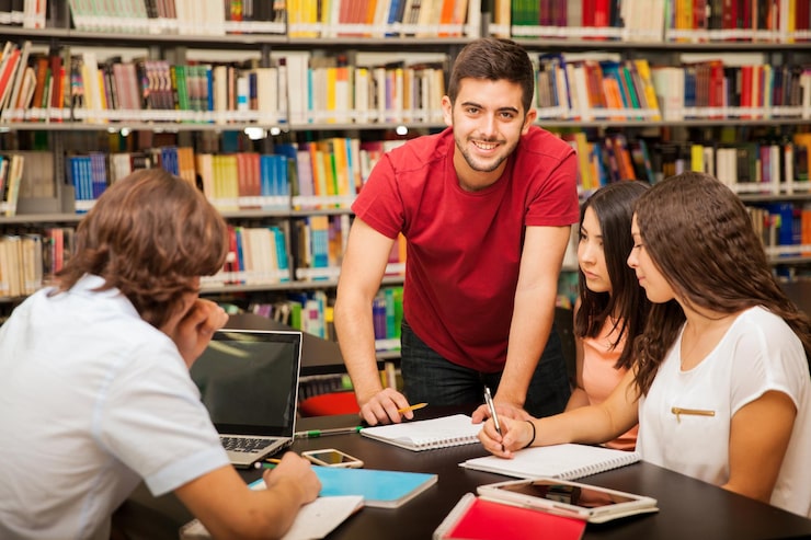 Foto gratuito bell'uomo latino che aiuta i suoi colleghi spiegando alcuni dei suoi lavori in biblioteca