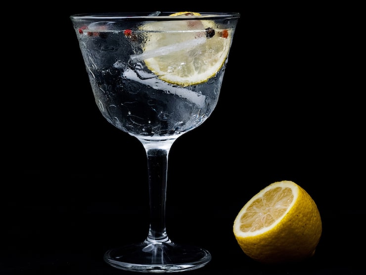 Foto gratuito bicchiere di gintonic con limone e ghiaccio isolato su una parete nera