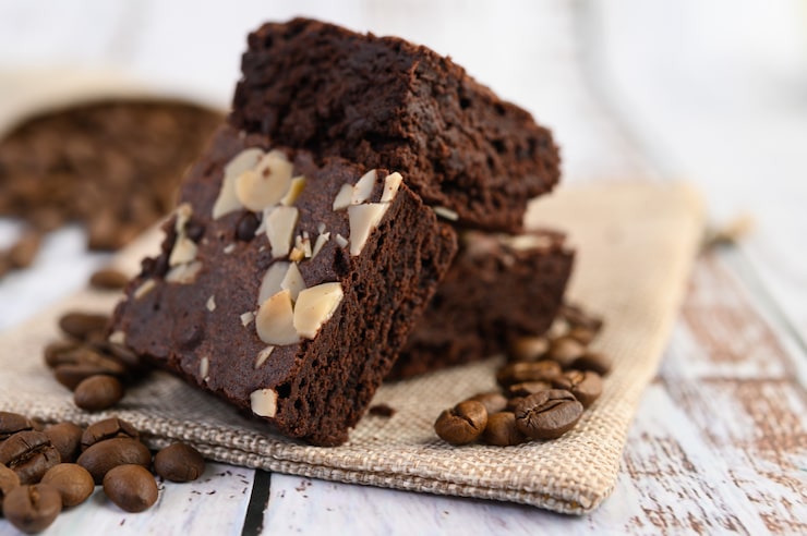 Foto gratuito brownies al cioccolato su tela di sacco e chicchi di caffè su un tavolo di legno.
