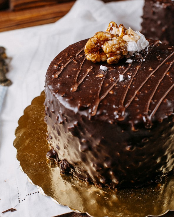 Foto gratuito close-up di una torta ricoperta di cioccolato e noci sul tavolo