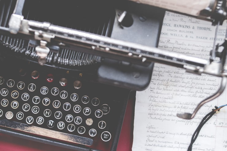 Foto gratuito colpo del primo piano di una vecchia macchina da scrivere vintage su una scrivania rossa con carta sul lato
