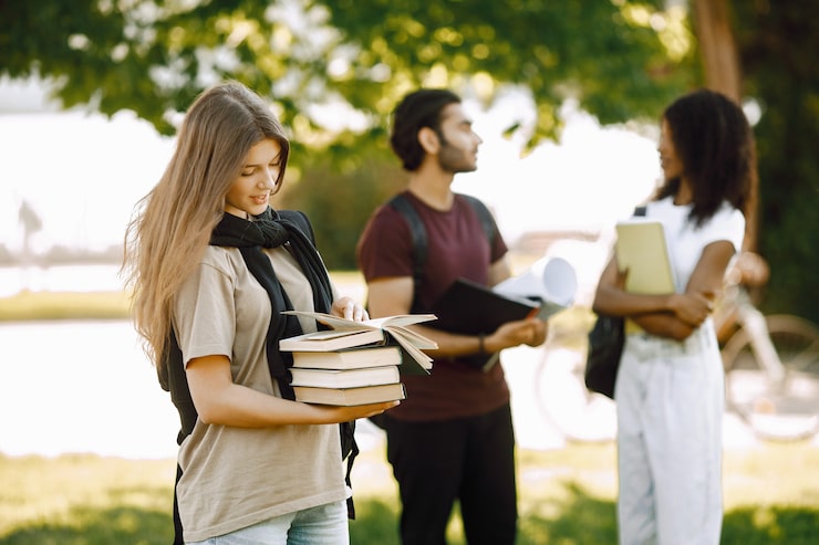 Foto gratuito concentrati su una ragazza caucasica che sta in piedi separatamente. gruppo di studenti internazionali in piedi insieme nel parco dell'università