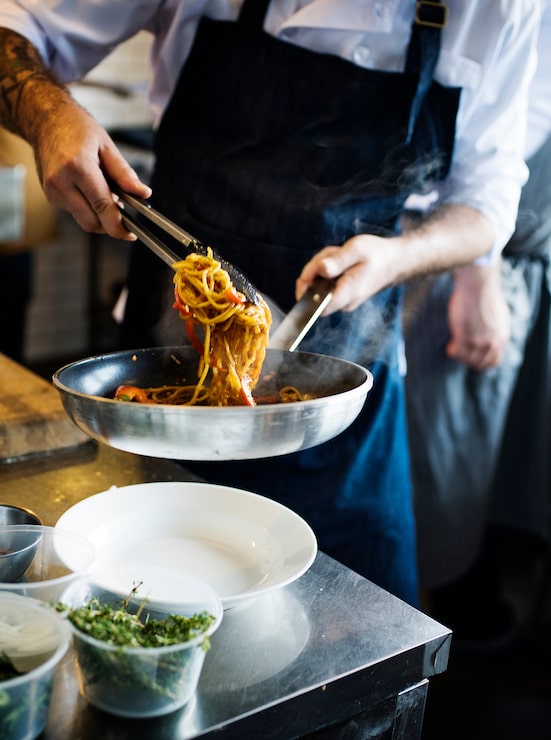Foto gratuito cuoco unico che cucina gli spaghetti in cucina