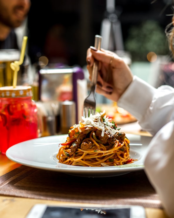 Foto gratuito donna mangia spaghetti di pasta con carne verde parmigiana vista laterale