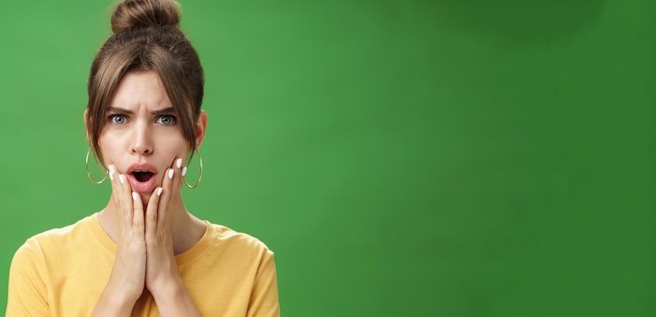 Foto gratuito donna scioccata che reagisce al brufolo che sembra disturbata e scontenta nello specchio tenendo le mani premute