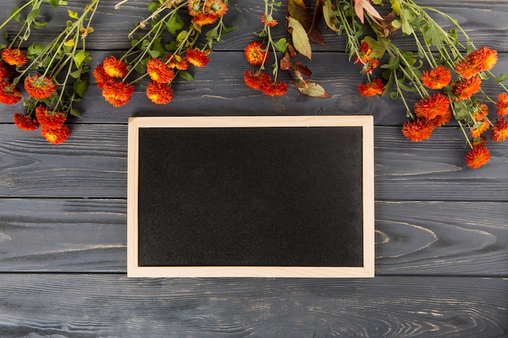 Foto gratuito fiori rossi con lavagna vuota sul tavolo di legno