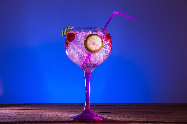 Foto gratuito gin tonic con lamponi e lime su sfondo blu
