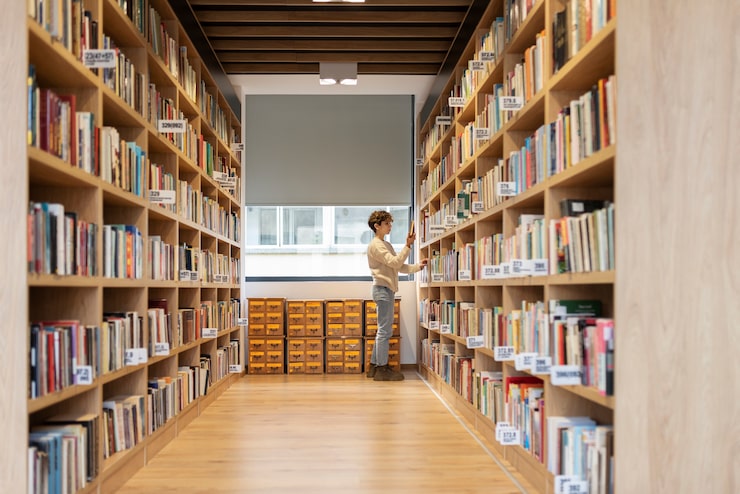 Foto gratuito giovane studente che cerca un libro in biblioteca