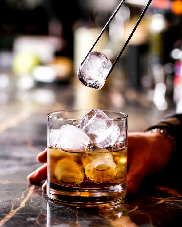 Foto gratuito il tender da bar aggiunge ghiaccio con clip in acciaio nel bicchiere da cocktail