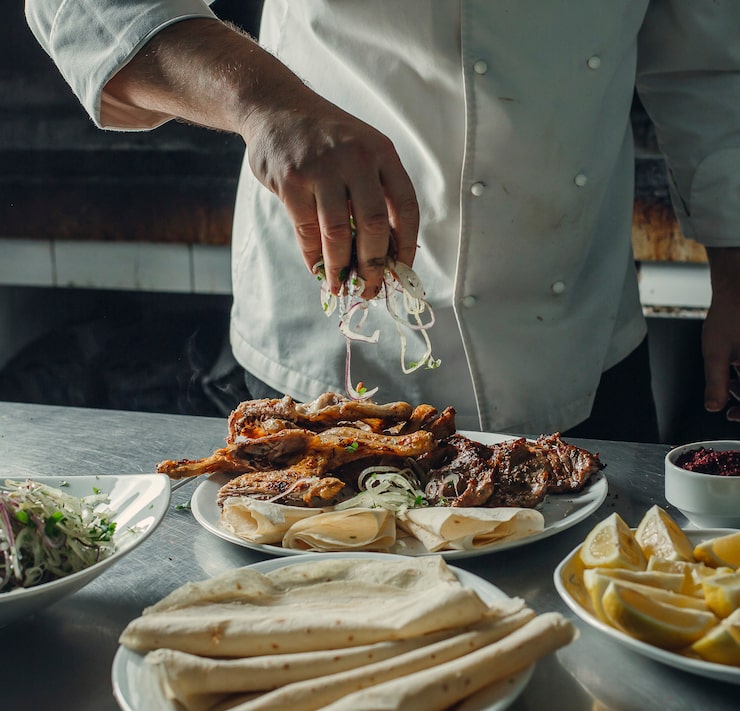 Foto gratuito lo chef spruzza anelli di cipolla sul piatto di kebab con pollo, agnello, focacce