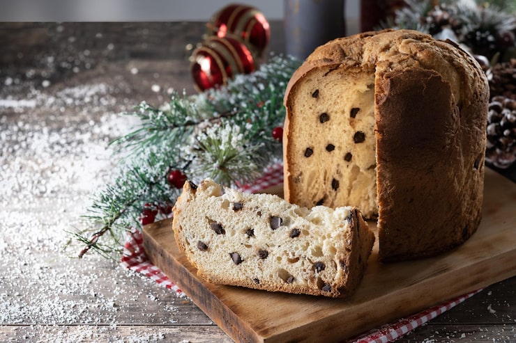 Foto gratuito panettone natalizio tradizionale con cravatta rossa e ornamenti natalizi su tavola di legno