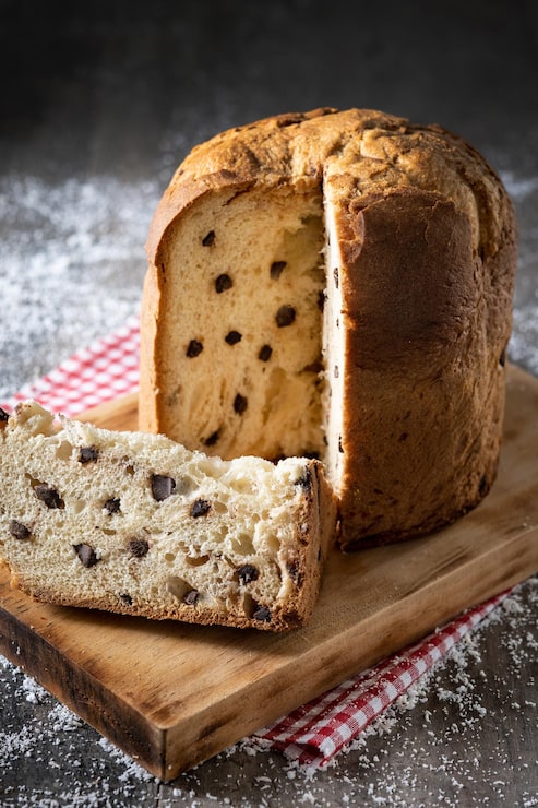 Foto gratuito panettone natalizio tradizionale con cravatta rossa e ornamenti natalizi su tavola di legno