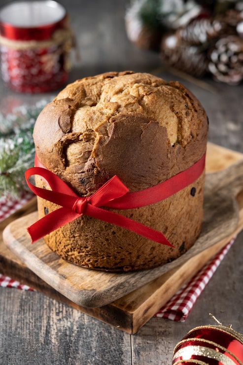 Foto gratuito panettone natalizio tradizionale con cravatta rossa su tavola di legno